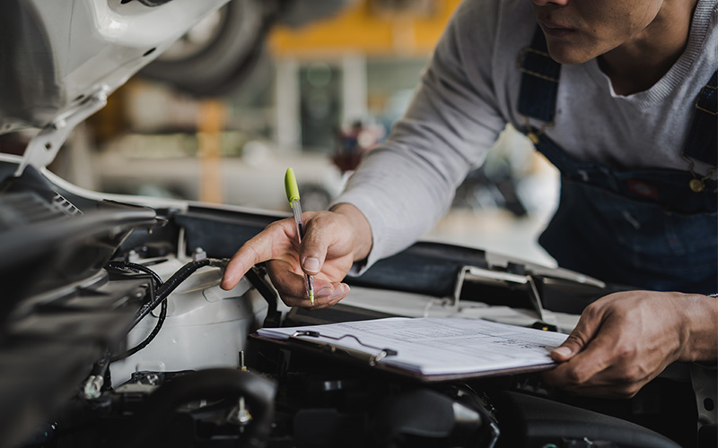 Engine inspection by a professional maintenance expert who has his checklist and a pen in hand