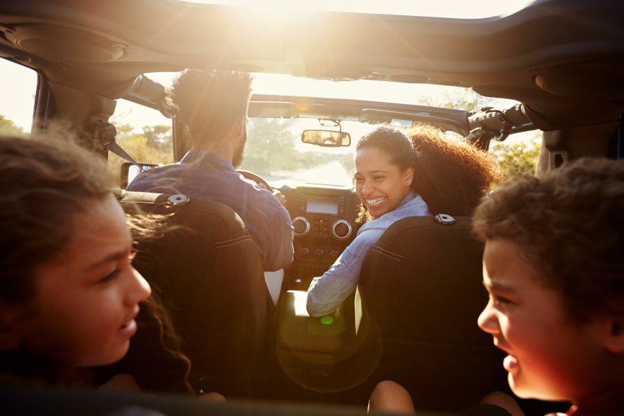 Buick GMC SUV is filled with a smiling happy family, ready to hit the road after summer road trip maintenance